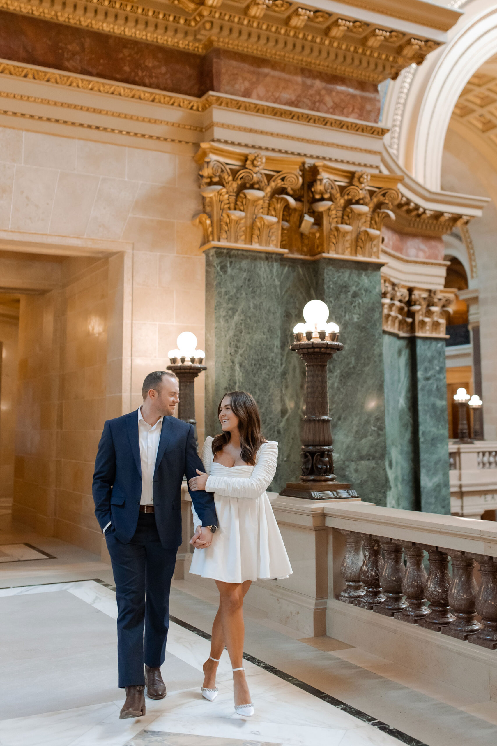 A couple in a suit + white dress take engagement photos in the Wisconsin State Capitol by Claire Neville Photography 