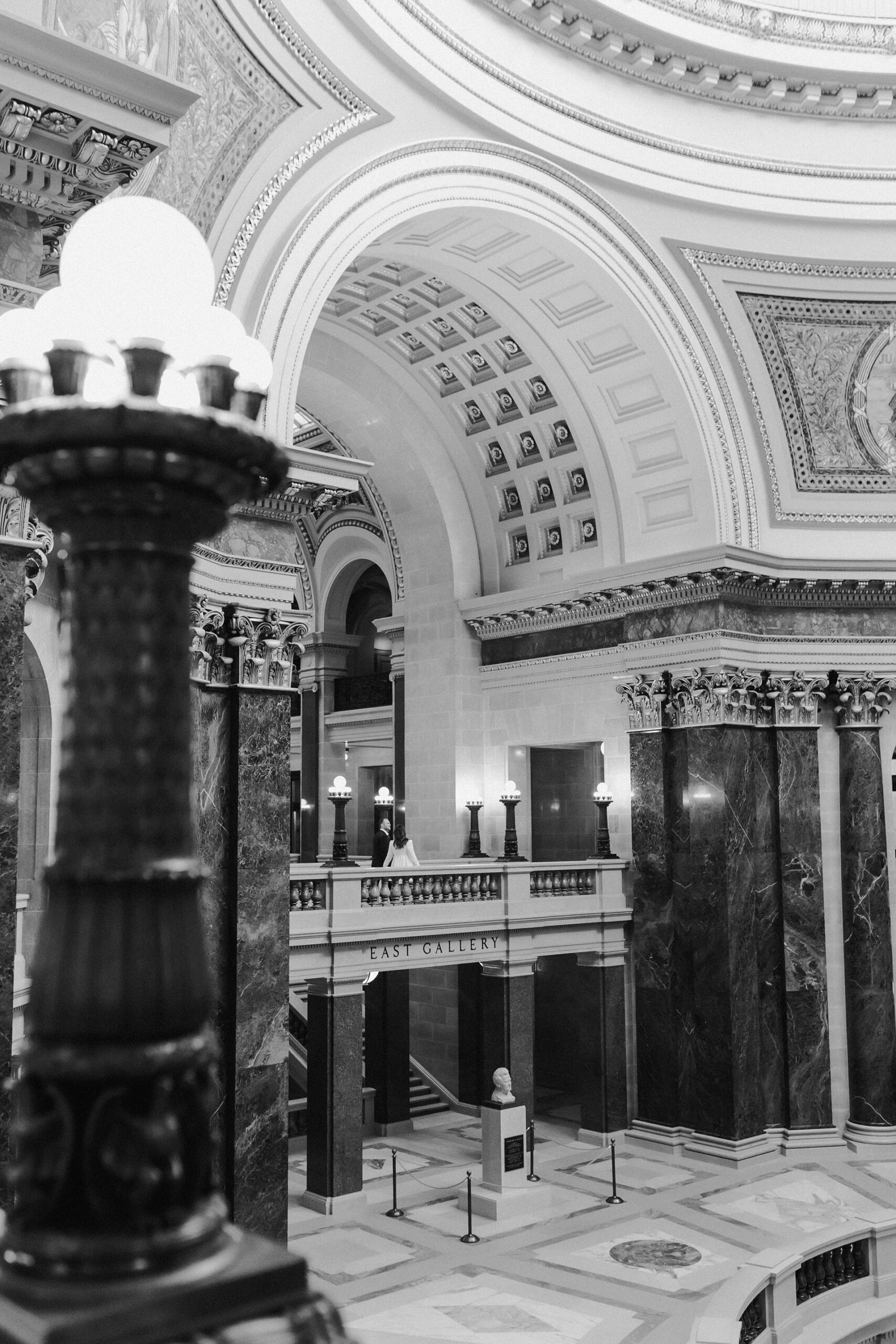 A couple in a suit + white dress take engagement photos in the Wisconsin State Capitol by Claire Neville Photography 