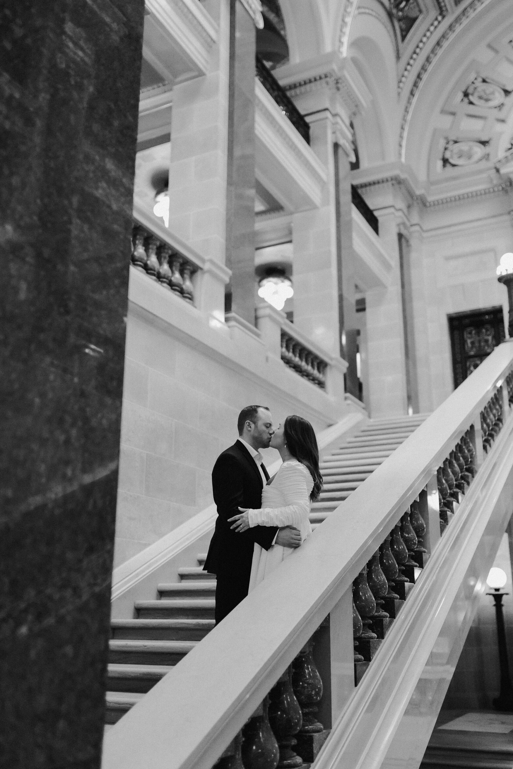 A couple in a suit + white dress take engagement photos in the Wisconsin State Capitol by Claire Neville Photography 