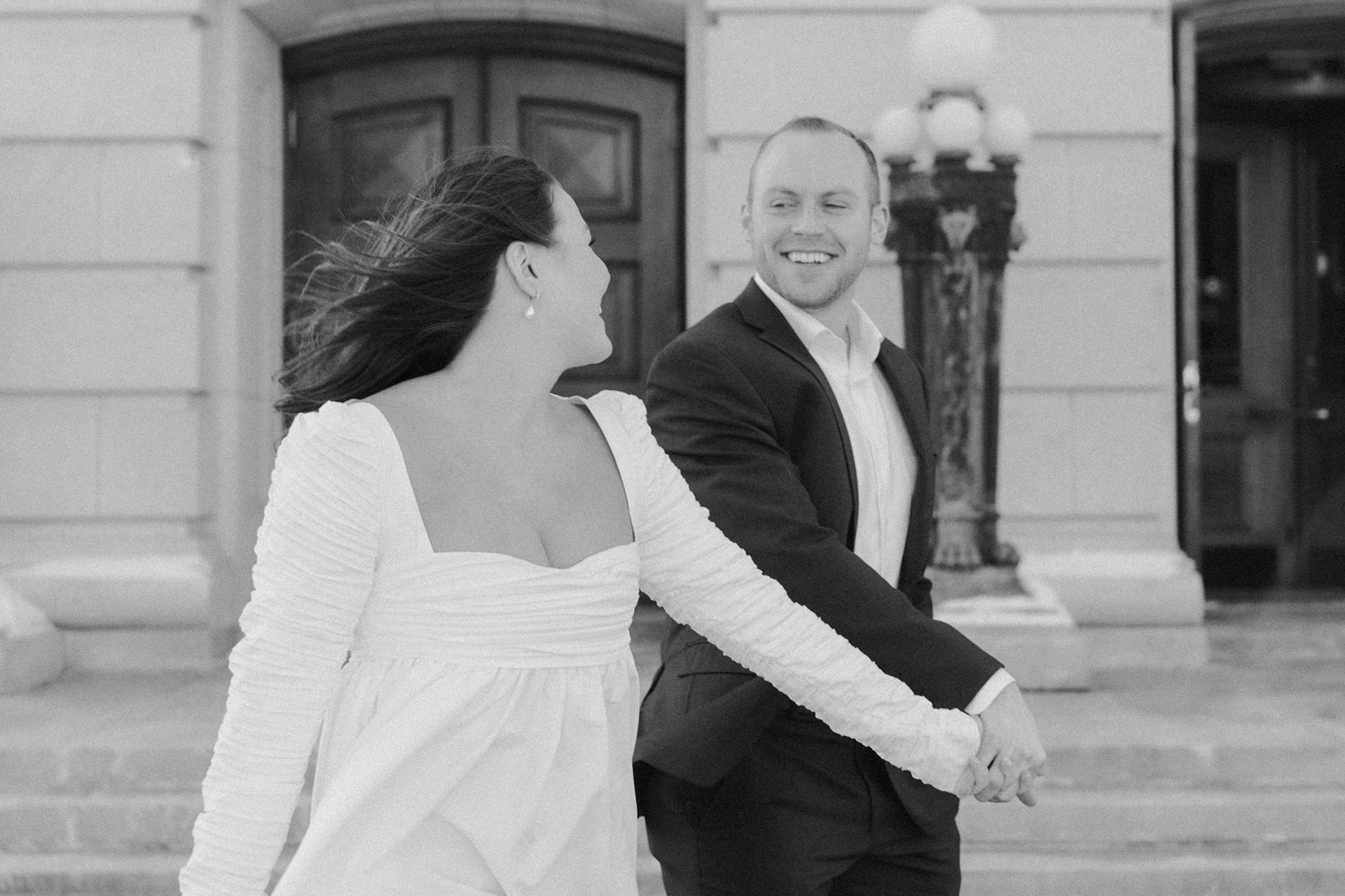 A couple in a suit + white dress take engagement photos outside the Wisconsin State Capitol by Claire Neville Photography 