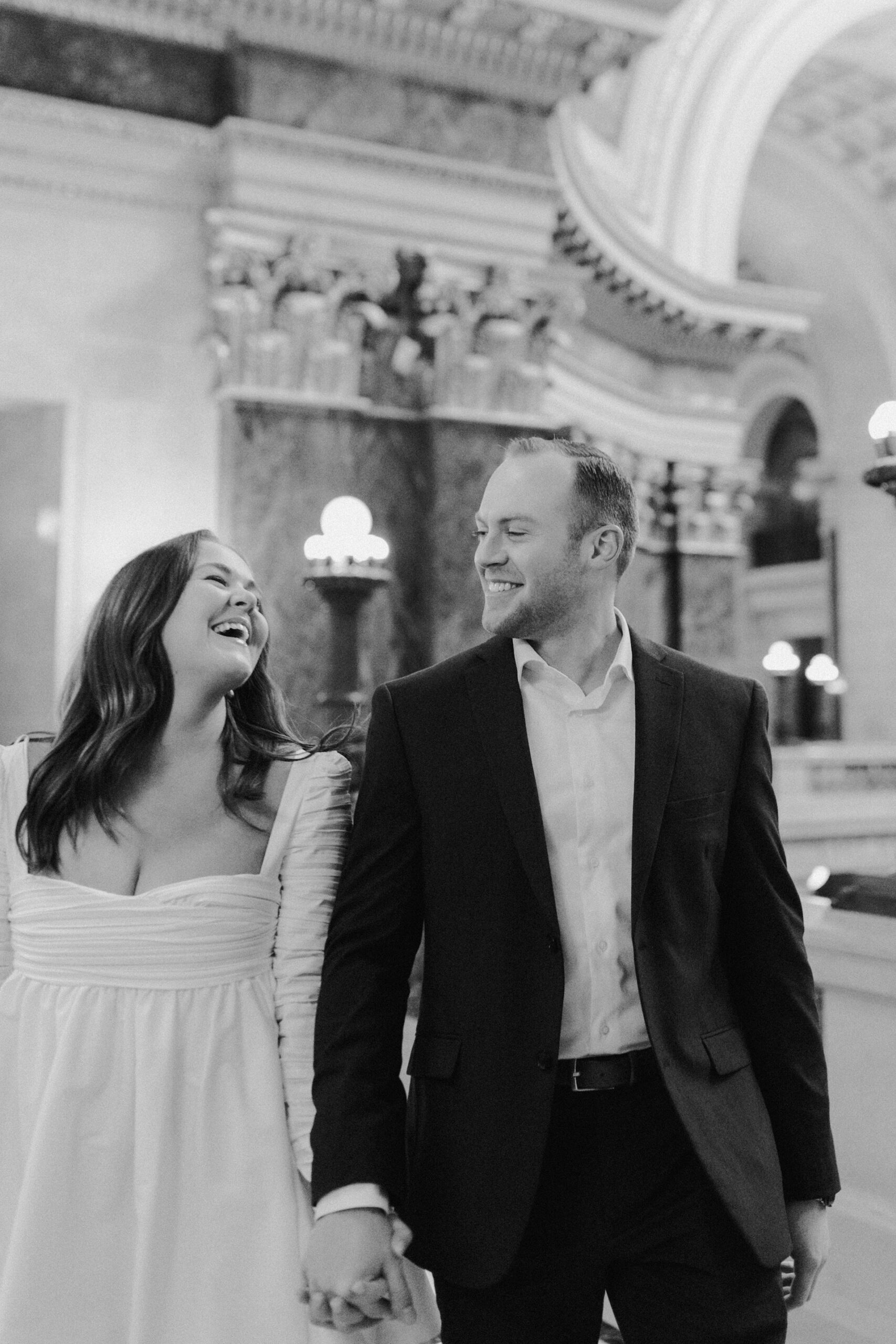 A couple in a suit + white dress take engagement photos in the Wisconsin State Capitol by Claire Neville Photography 