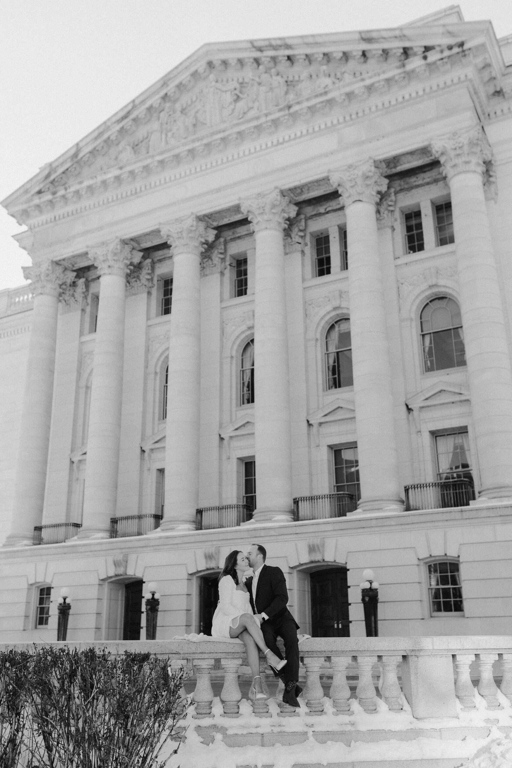 A couple in a suit + white dress take engagement photos outside the Wisconsin State Capitol by Claire Neville Photography 