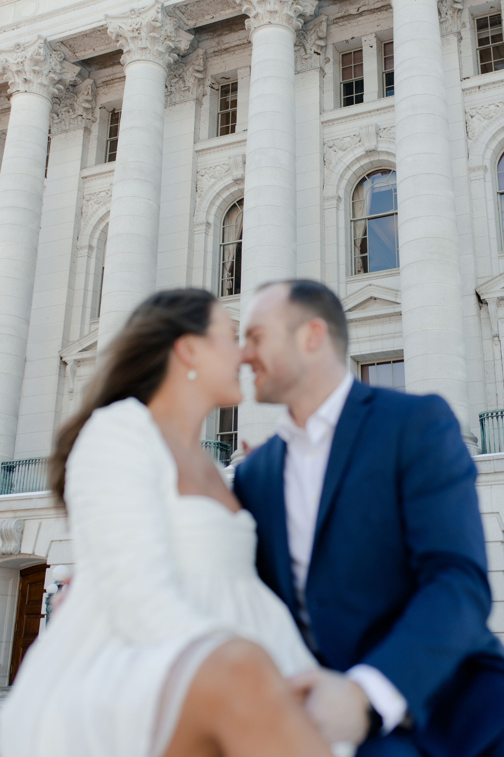 A couple in a suit + white dress take engagement photos outside the Wisconsin State Capitol by Claire Neville Photography 