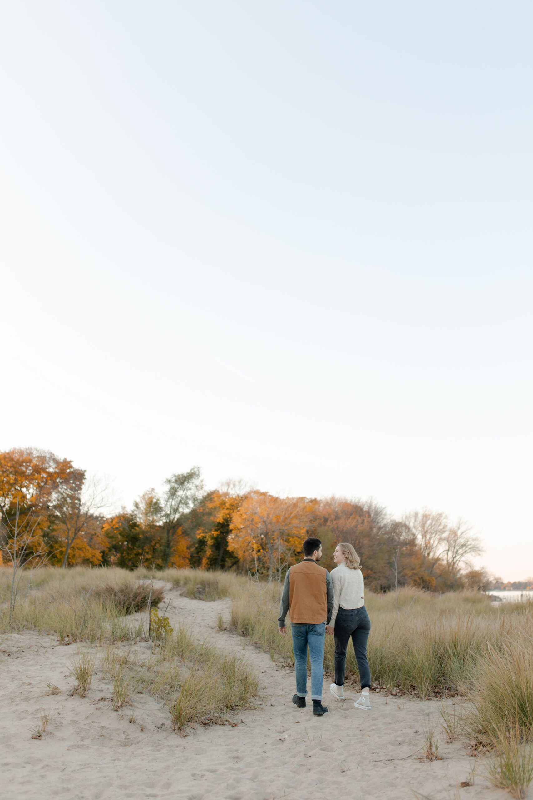 A couple poses in Evanston Illinois in front of an old lighthouse and beautiful sunset for an engagement session with Claire Neville photography. 