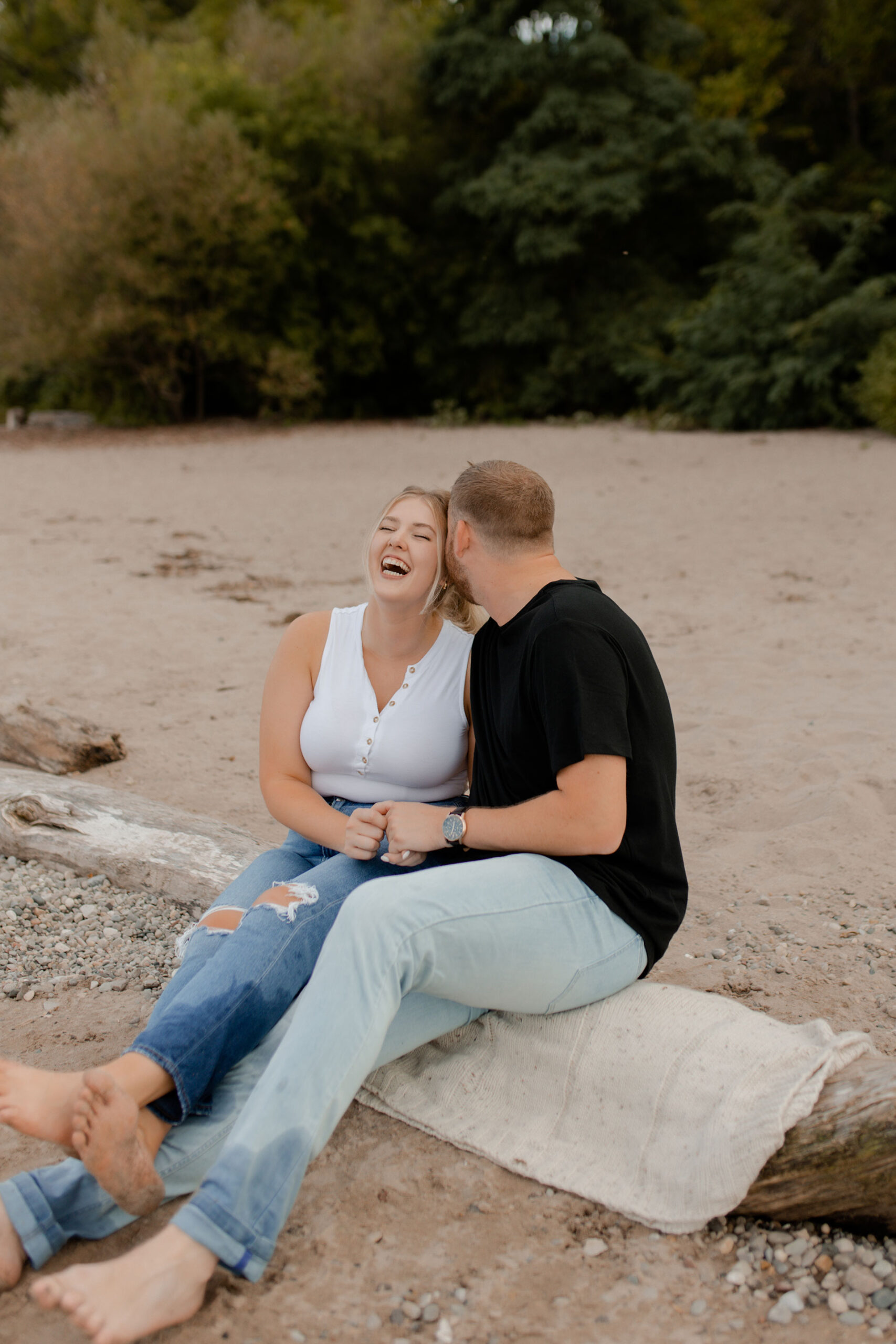 A couple along the beach in milwaukee posing for engagement photos that are documentary style captured by Claire Neville Photography