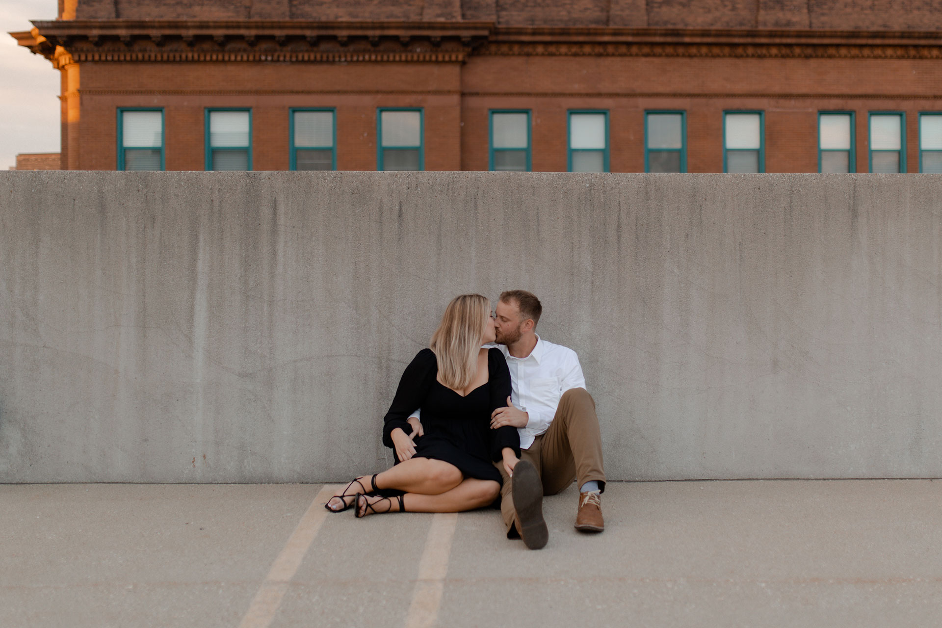 A couple on a parking garage in milwaukee posing for engagement photos that are documentary style captured by Claire Neville Photography