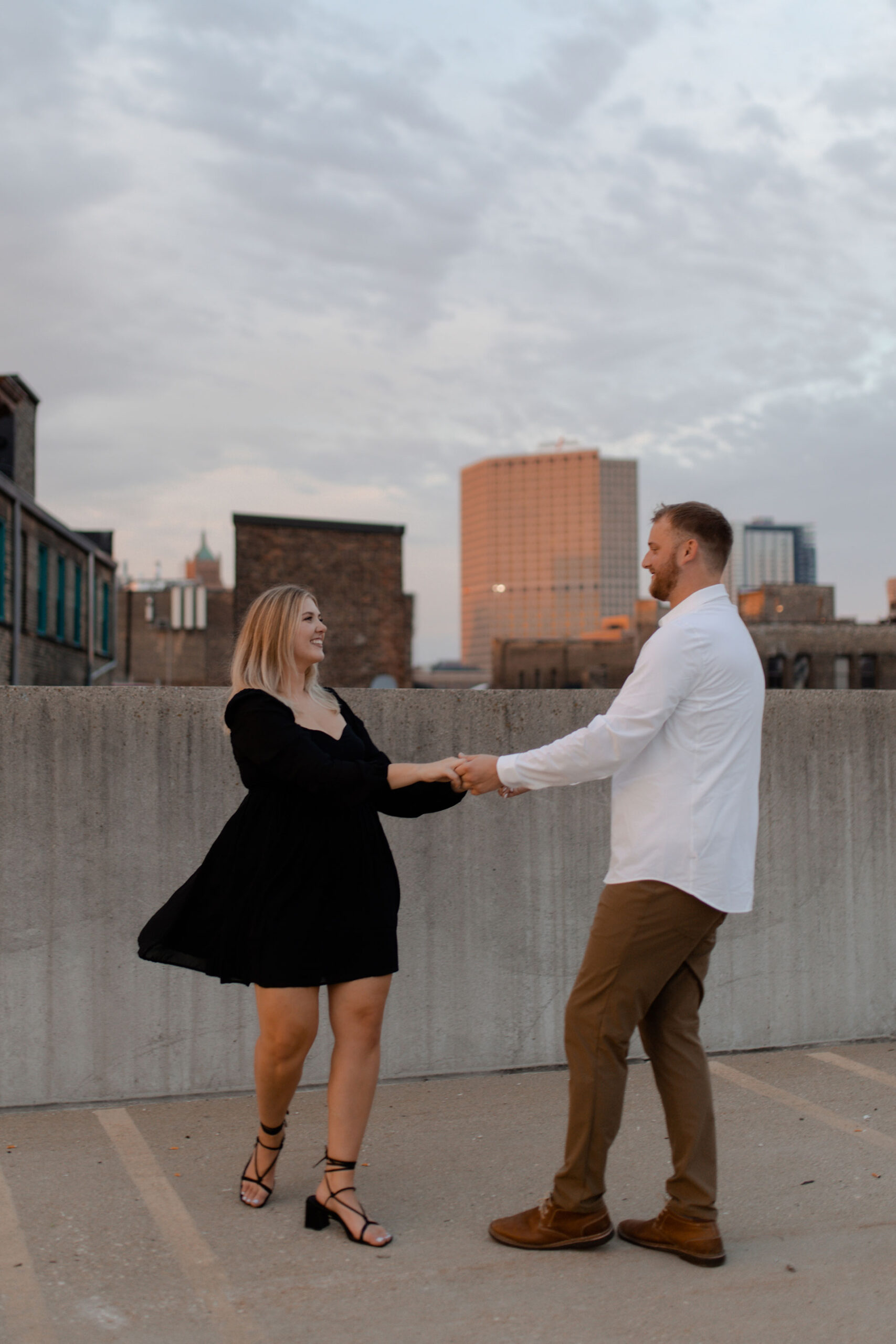 A couple on a parking garage in milwaukee posing for engagement photos that are documentary style captured by Claire Neville Photography